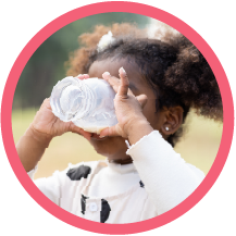 girl drinking out of a glass of milk while standing outside